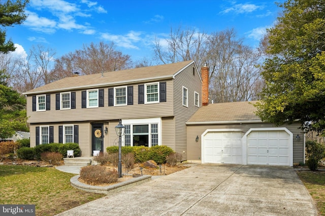 colonial house featuring a garage, driveway, and a chimney