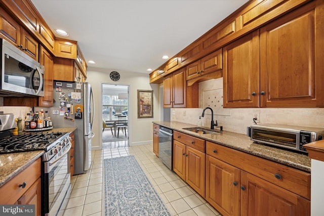 kitchen with a sink, stone countertops, tasteful backsplash, appliances with stainless steel finishes, and light tile patterned floors