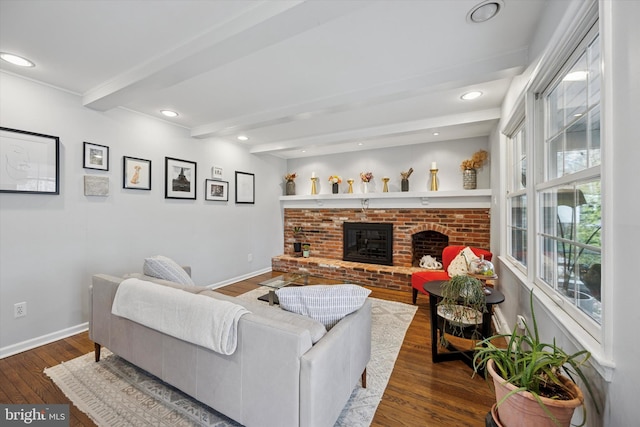 living room with beam ceiling, a brick fireplace, baseboards, and wood-type flooring