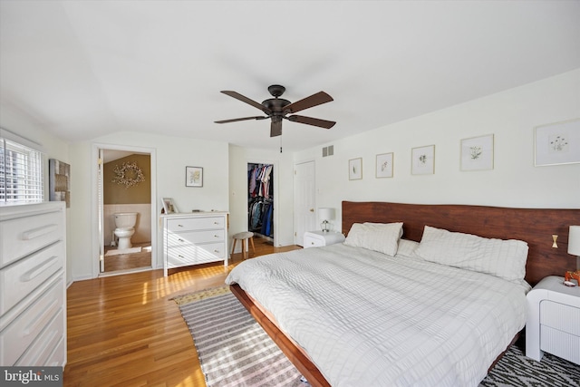 bedroom featuring visible vents, a walk in closet, light wood-style flooring, a ceiling fan, and a closet