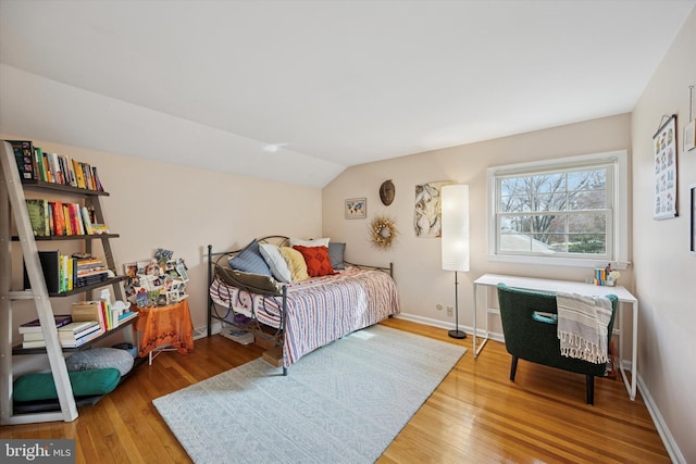 bedroom featuring baseboards, lofted ceiling, and wood-type flooring