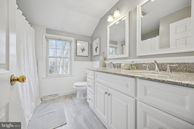 full bath with a sink, visible vents, lofted ceiling, and toilet