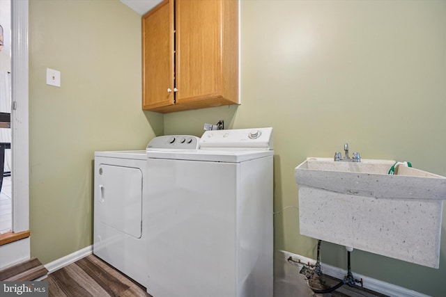 laundry area with baseboards, washer and clothes dryer, wood finished floors, cabinet space, and a sink