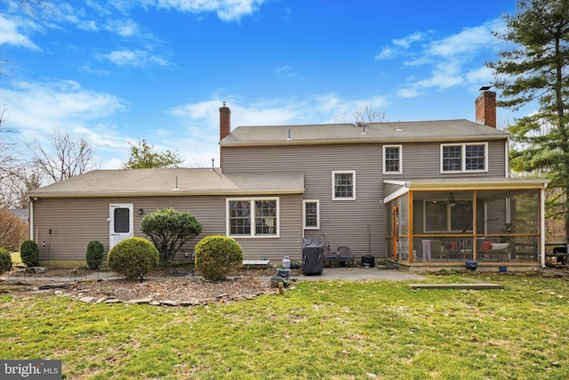 back of house featuring a yard, a chimney, a patio, and a sunroom