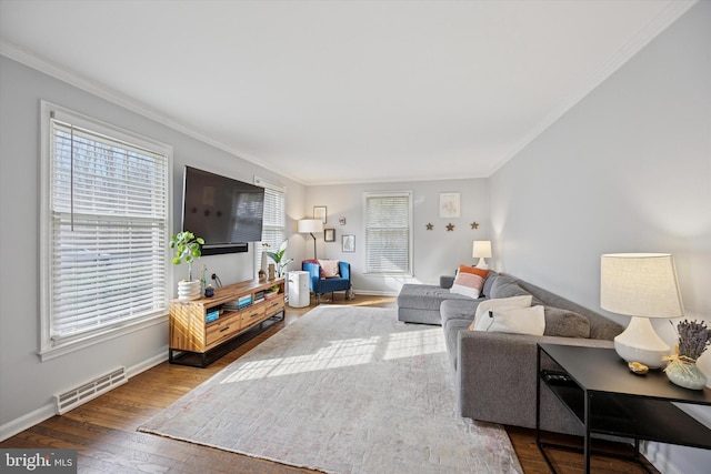 living room with visible vents, ornamental molding, baseboards, and wood-type flooring