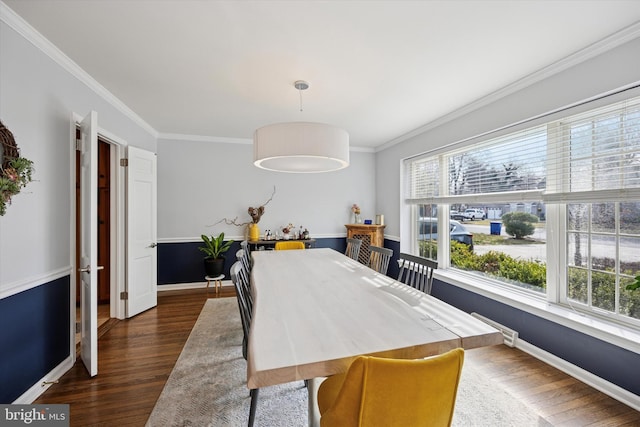 dining room with dark wood finished floors, crown molding, and baseboards