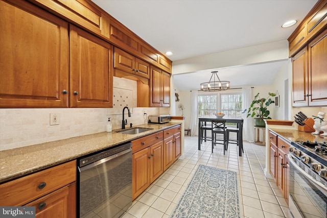 kitchen featuring a sink, an inviting chandelier, brown cabinetry, dishwasher, and stainless steel gas range