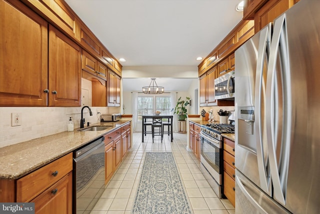 kitchen featuring light tile patterned floors, a sink, appliances with stainless steel finishes, tasteful backsplash, and brown cabinets