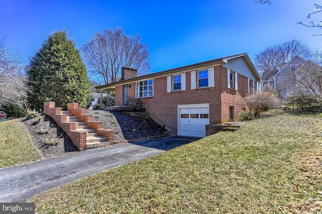 ranch-style home featuring a front yard, an attached garage, a chimney, aphalt driveway, and brick siding