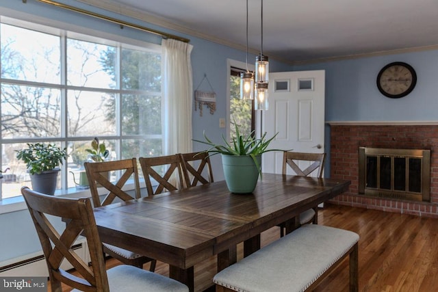 dining area featuring a brick fireplace, wood finished floors, and crown molding