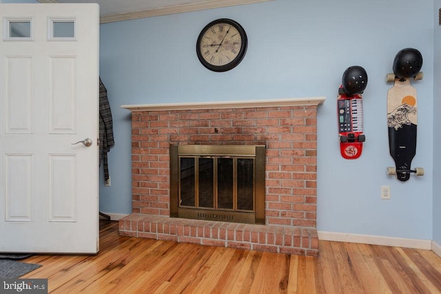 unfurnished living room featuring ornamental molding, a fireplace, baseboards, and wood finished floors