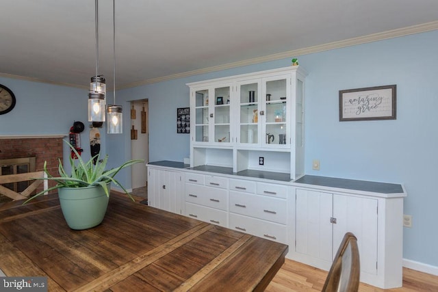 dining area featuring light wood-type flooring, baseboards, and crown molding