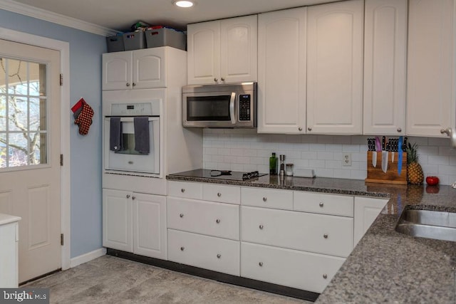 kitchen with oven, stainless steel microwave, white cabinets, crown molding, and black electric stovetop