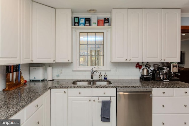 kitchen with a sink, dishwasher, dark stone countertops, and white cabinetry