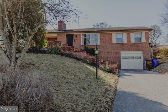 single story home featuring brick siding, driveway, a chimney, and a garage