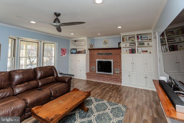 living area featuring ornamental molding, recessed lighting, a fireplace, wood finished floors, and a ceiling fan