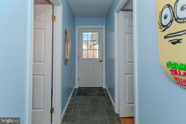 doorway with stone finish flooring and baseboards