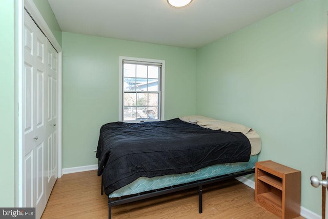 bedroom with a closet, baseboards, and light wood-style floors