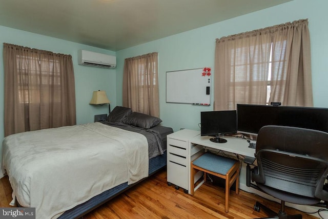 bedroom with wood finished floors and a wall mounted AC