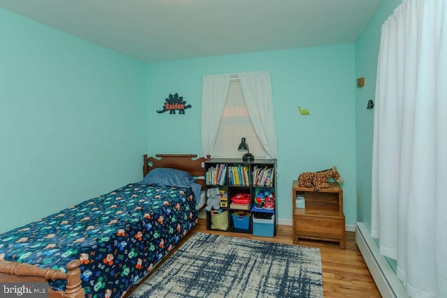 bedroom with baseboard heating, baseboards, and wood finished floors