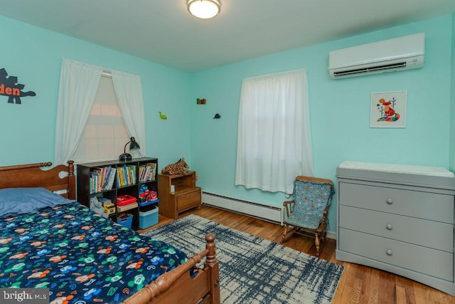 bedroom with a baseboard radiator, wood finished floors, and a wall mounted AC