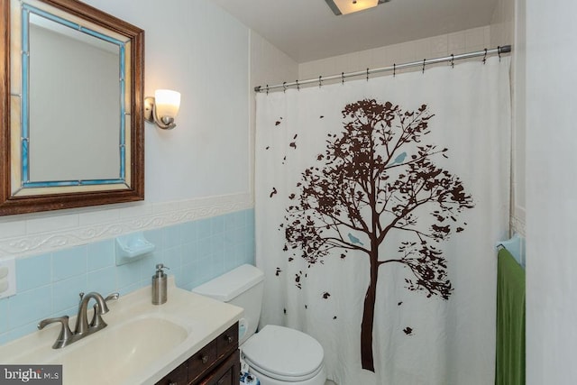 full bathroom with toilet, a shower with shower curtain, tile walls, wainscoting, and vanity