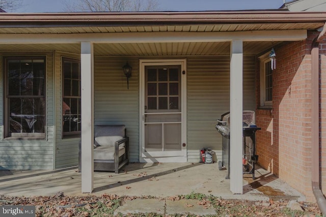 view of exterior entry with a porch and brick siding