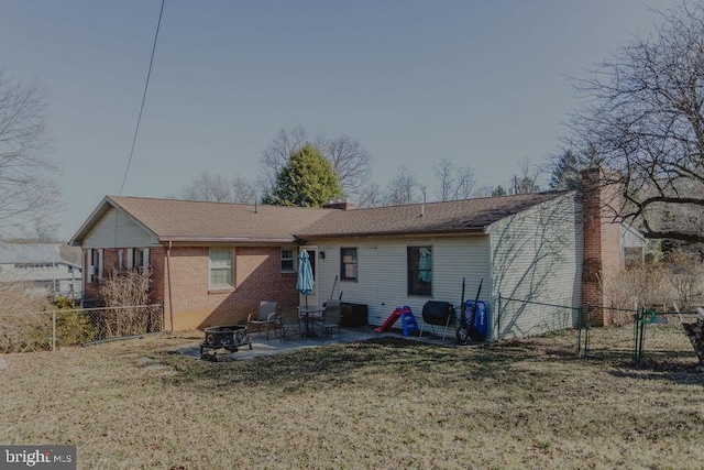 back of property featuring brick siding, fence, an outdoor fire pit, a yard, and a patio area