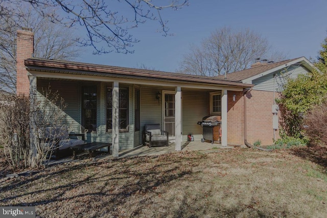 rear view of house with brick siding and a chimney