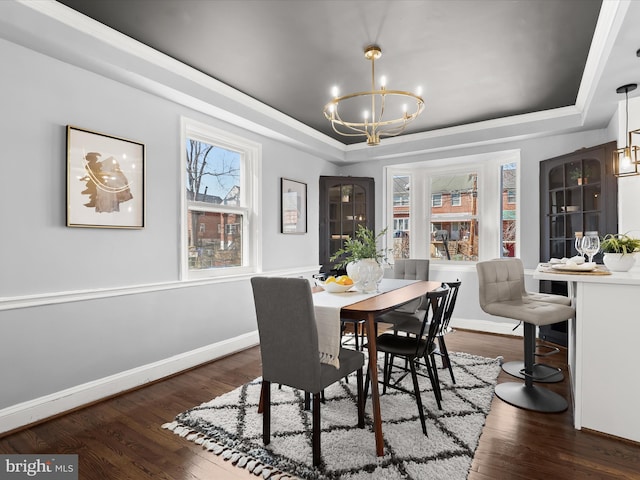 dining area with an inviting chandelier, baseboards, a tray ceiling, and wood finished floors