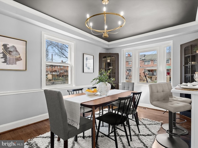 dining area with a raised ceiling, plenty of natural light, and wood finished floors