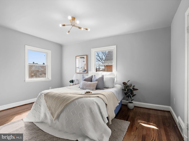 bedroom with an inviting chandelier, baseboards, and wood finished floors