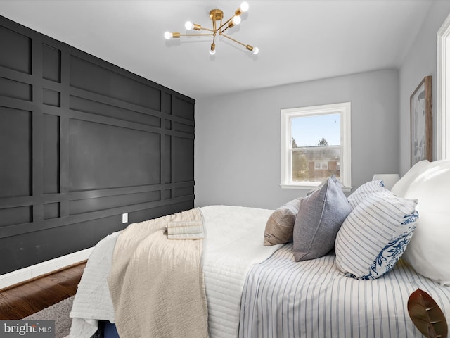 bedroom with a chandelier, a decorative wall, and wood finished floors