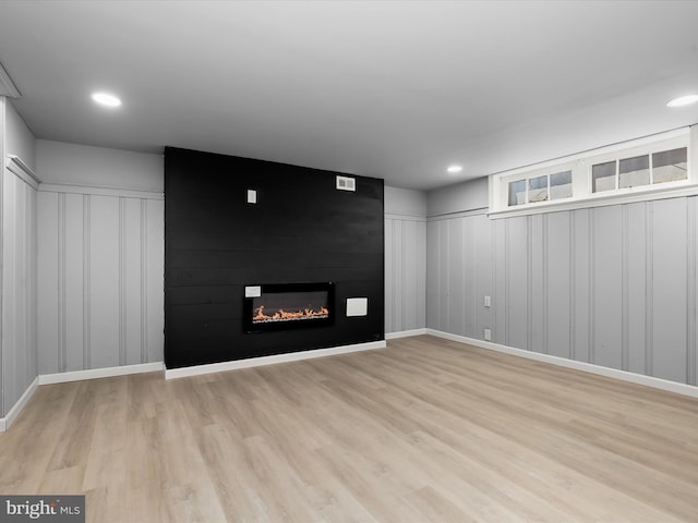 unfurnished living room with recessed lighting, baseboards, a large fireplace, and light wood-style flooring