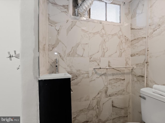 bathroom featuring a marble finish shower, toilet, and vanity