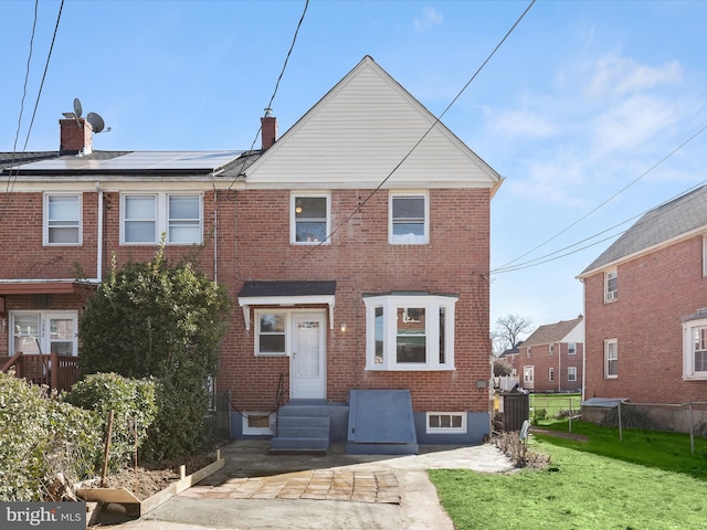 townhome / multi-family property featuring entry steps, a front lawn, fence, and brick siding