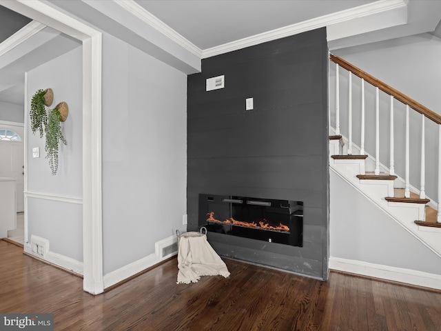 interior space with visible vents, a large fireplace, stairs, ornamental molding, and wood finished floors