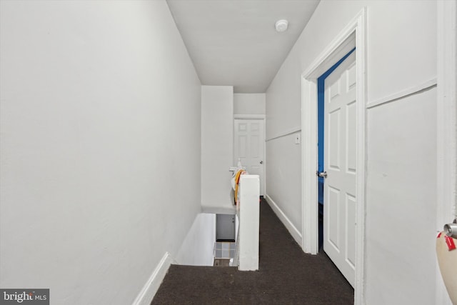 hallway with baseboards, carpet flooring, and an upstairs landing