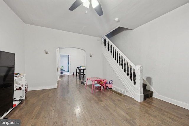 game room featuring arched walkways, ceiling fan, baseboards, and hardwood / wood-style flooring