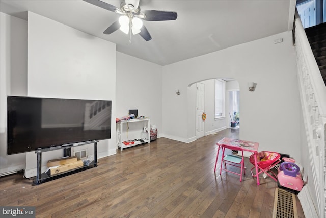 rec room with hardwood / wood-style flooring, ceiling fan, arched walkways, and baseboards