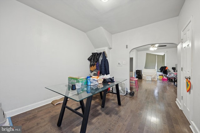 office space featuring arched walkways, ceiling fan, dark wood-style flooring, and baseboards