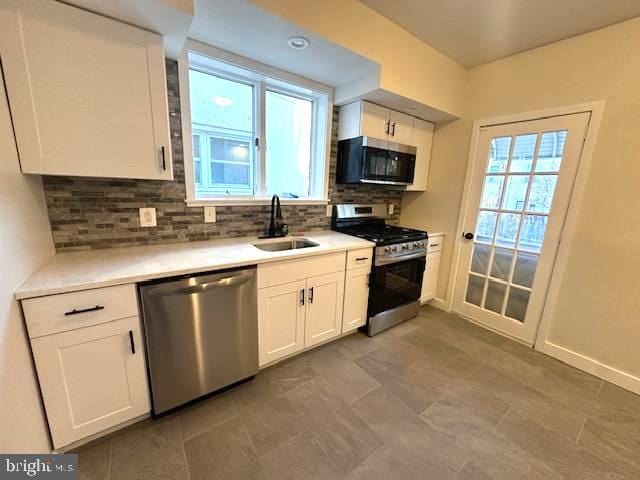 kitchen with decorative backsplash, white cabinetry, stainless steel appliances, and a sink