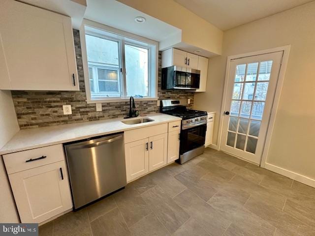 kitchen with a sink, white cabinetry, light countertops, appliances with stainless steel finishes, and backsplash