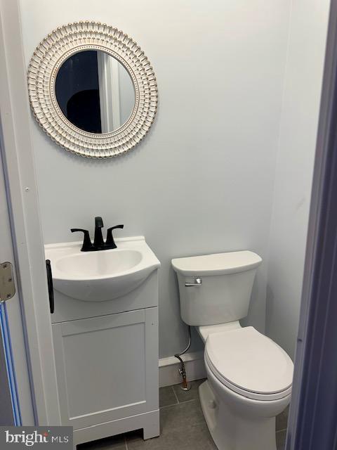 bathroom with toilet, tile patterned flooring, baseboards, and vanity