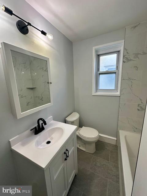 bathroom with toilet, baseboards, a bathtub, and vanity