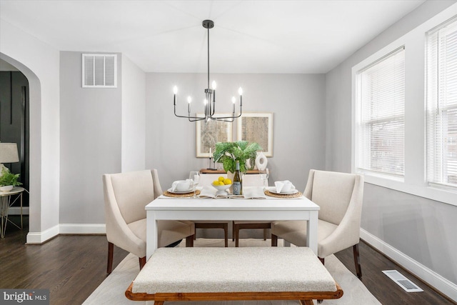 dining room featuring arched walkways, visible vents, and baseboards