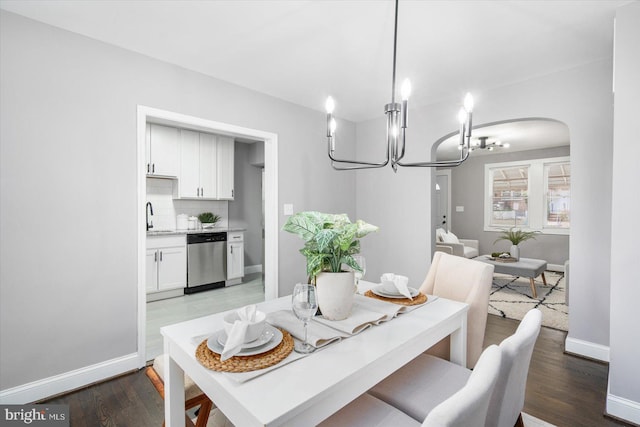 dining space with arched walkways, wood finished floors, and baseboards