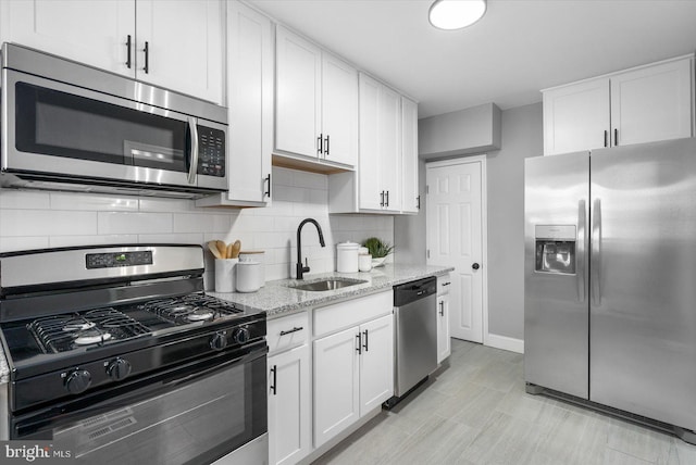 kitchen featuring white cabinets, backsplash, stainless steel appliances, and a sink