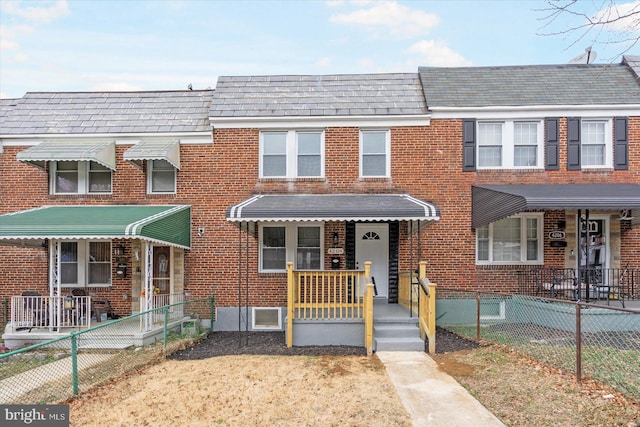 multi unit property featuring fence, mansard roof, and brick siding