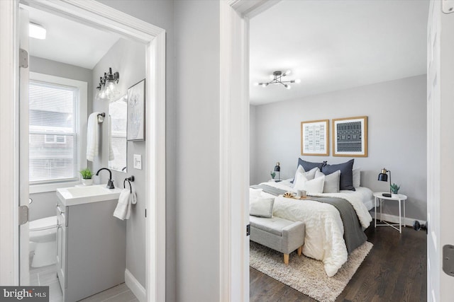 bedroom with dark wood-style flooring, a sink, and baseboards